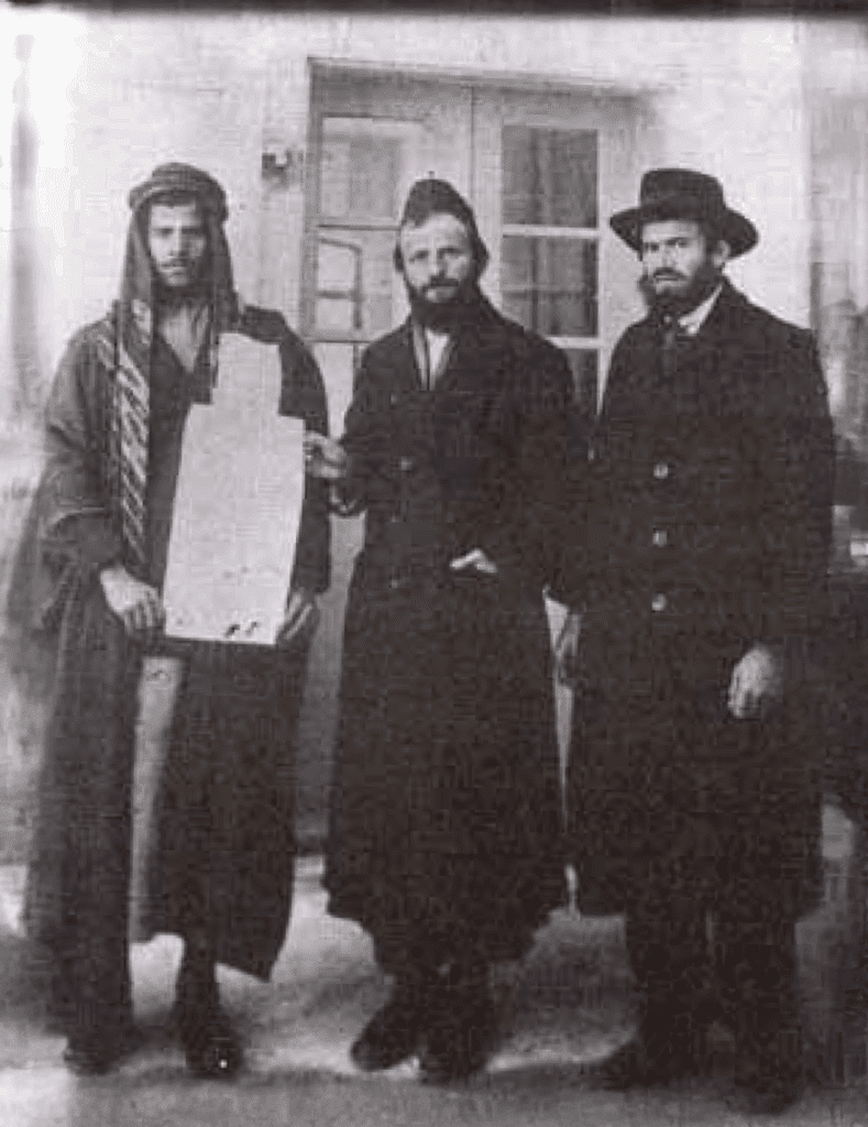 ר' משה פרוש מקבל את ה'קושאן' של אדמת "נחלת ישראל" מהמוכר הערבי. מימין – איש המעש והחזון רבי יוסף לוי חגיז. צילום: לא ידוע.