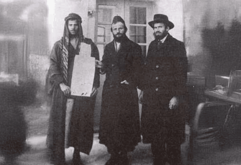 ר' משה פרוש מקבל את ה'קושאן' של אדמת "נחלת ישראל" מהמוכר הערבי. מימין – איש המעש והחזון רבי יוסף לוי חגיז. צילום: לא ידוע.