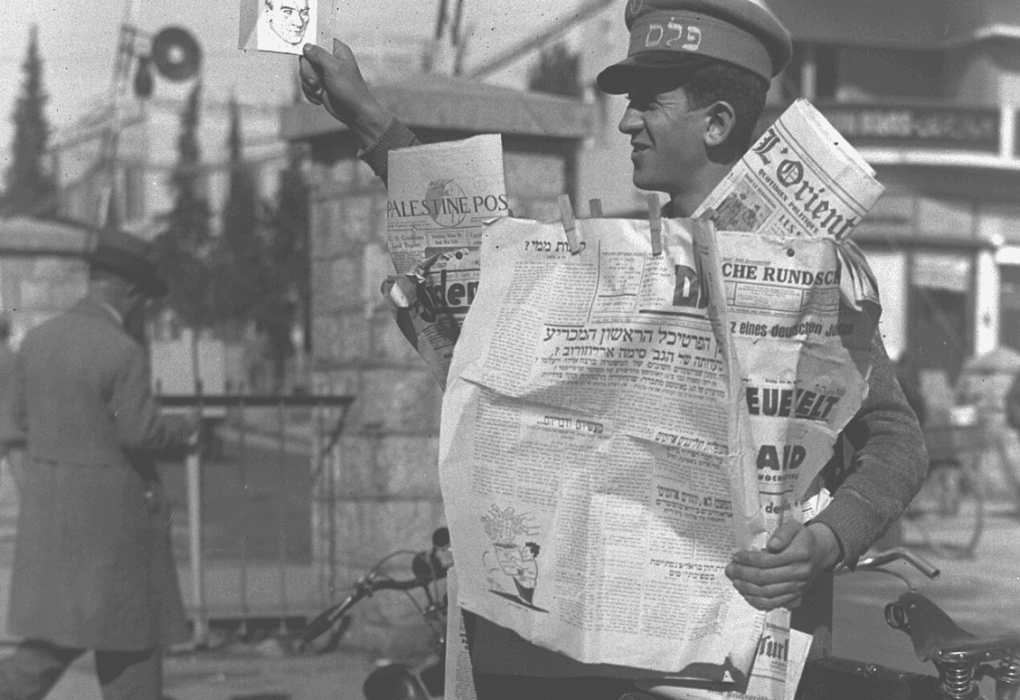 מוכר עיתונים מציג את הדף הראשון של חזית העם מ-8 בינואר 1934. צילום: זולטן קלוגר.