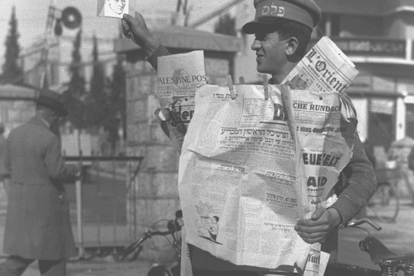 מוכר עיתונים מציג את הדף הראשון של חזית העם מ-8 בינואר 1934. צילום: זולטן קלוגר.