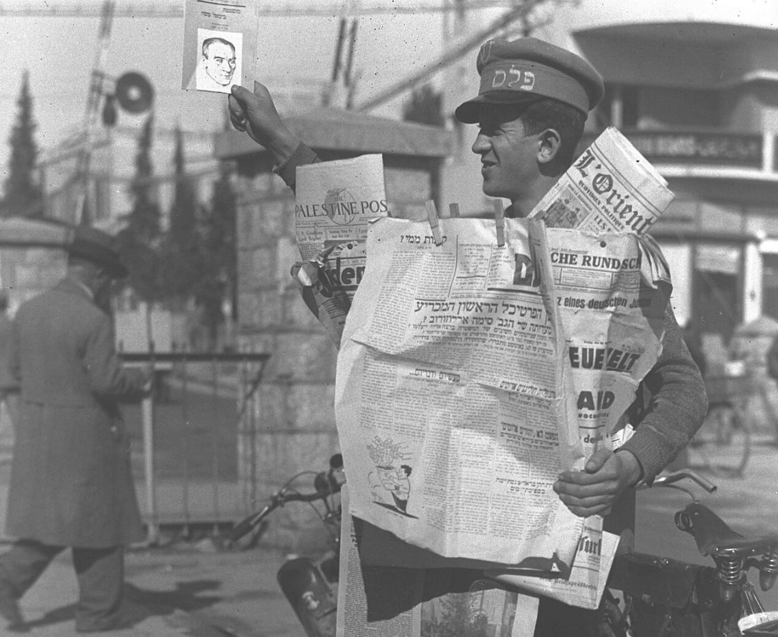 מוכר עיתונים מציג את הדף הראשון של חזית העם מ-8 בינואר 1934. צילום: זולטן קלוגר.